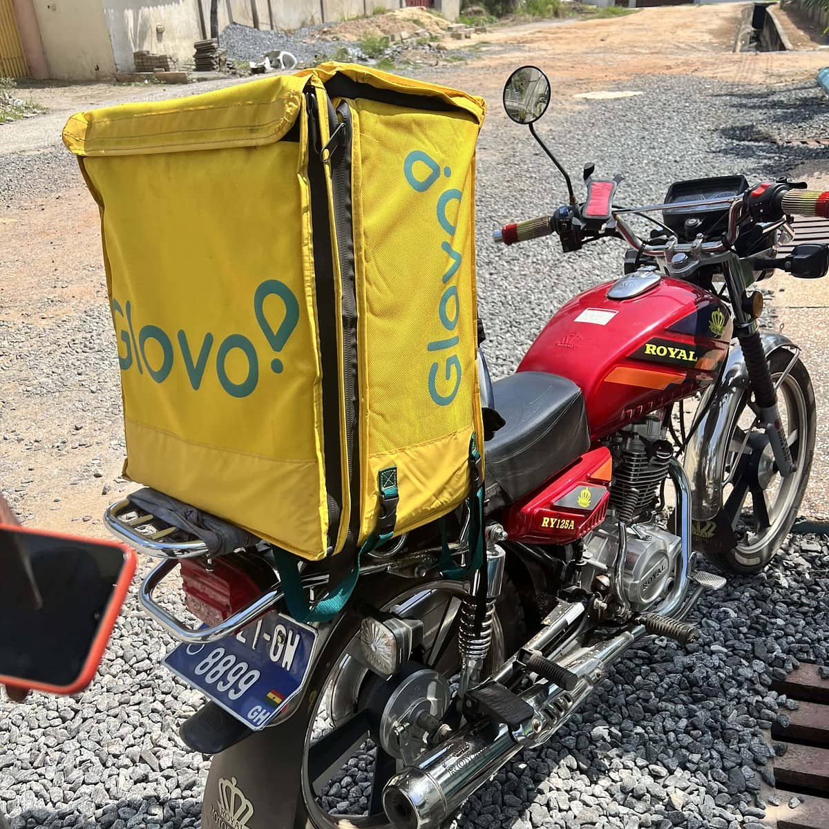A red motorcyle with a Glovo-branded carrier bag attached to the backseat of the motorcyle.