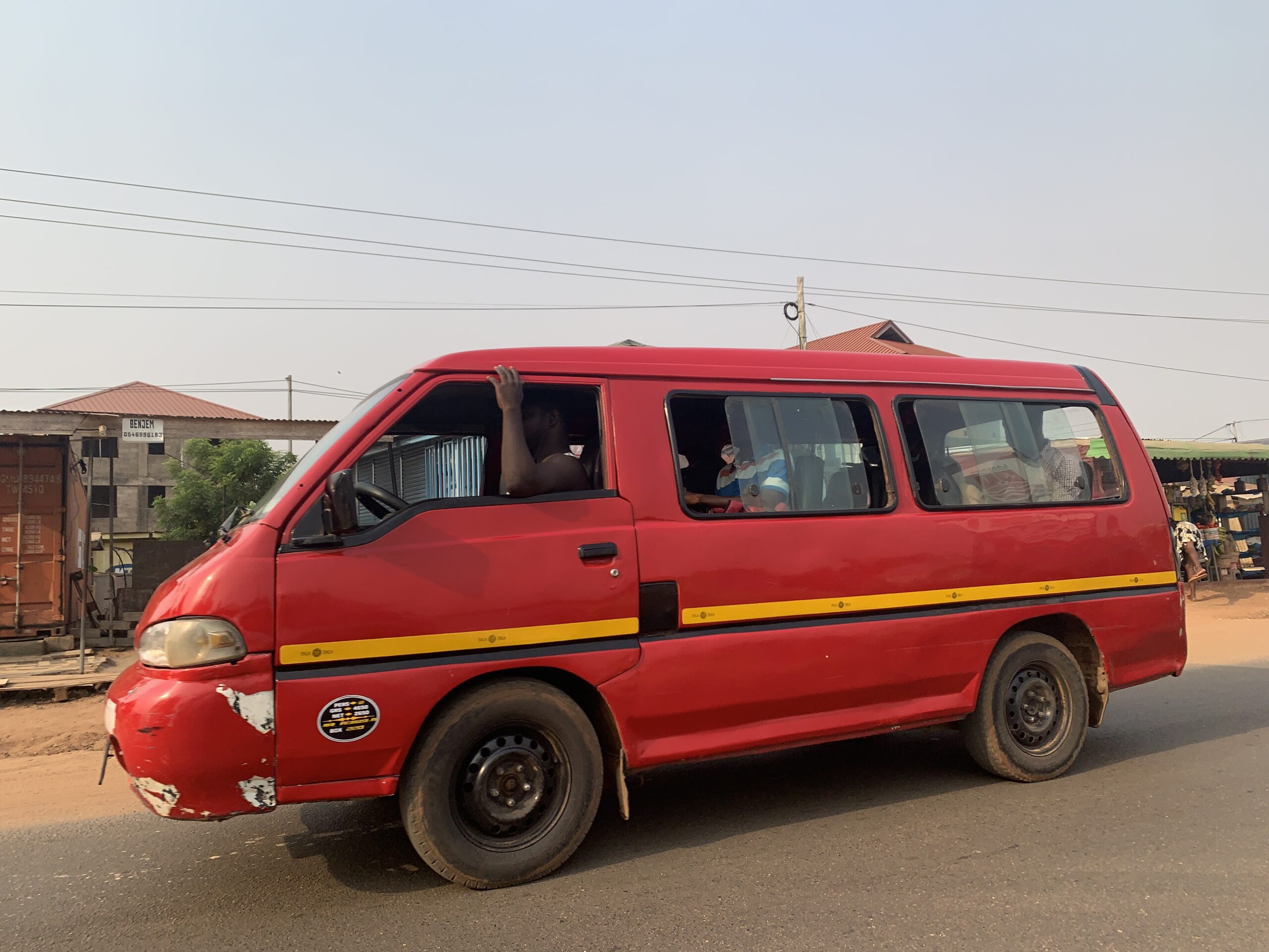 A red tro-tro driving on the road in Accra.