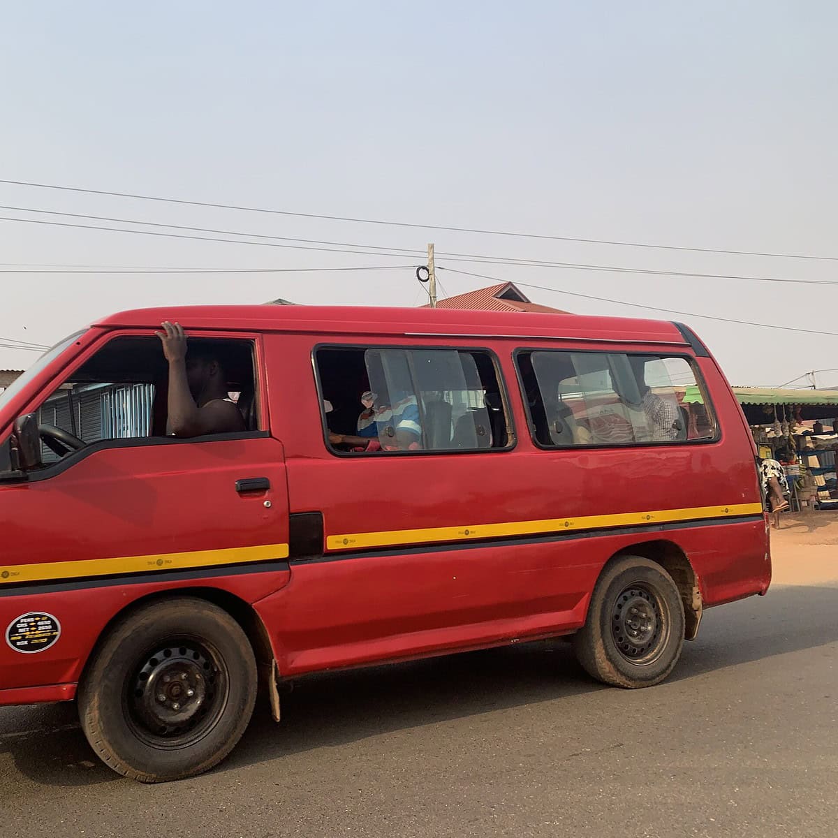 A red tro-tro driving on the road in Accra.