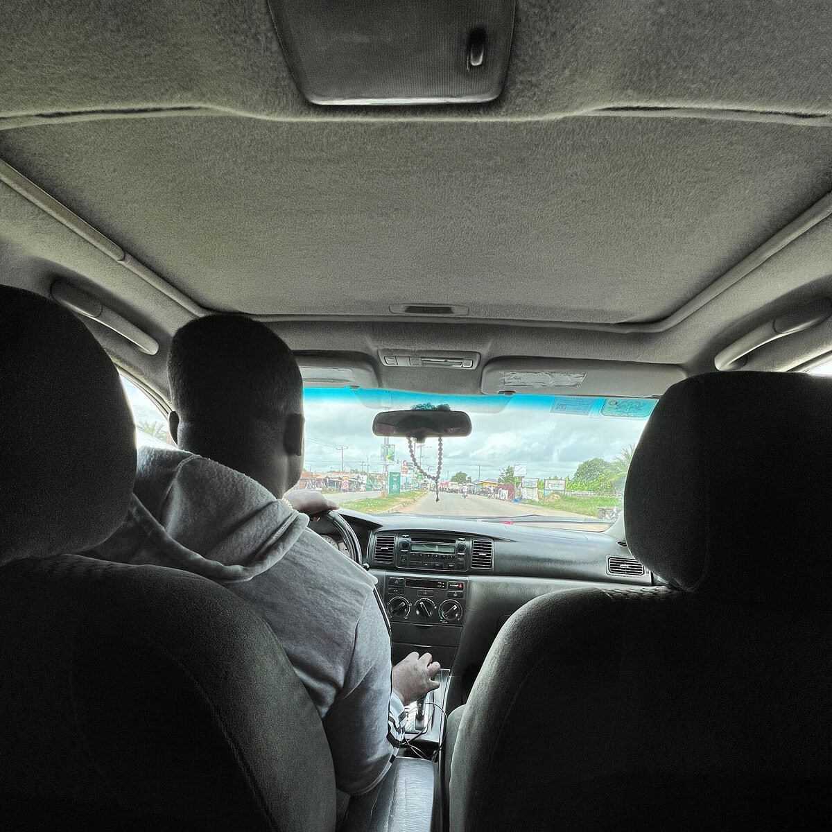 A driver in a gray hoodie driving a taxi car. 