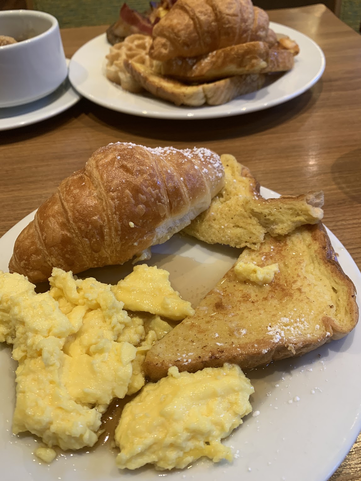 Breakfast plate consisting of french toast, scrambled eggs, and a croissant on the cruise ship.