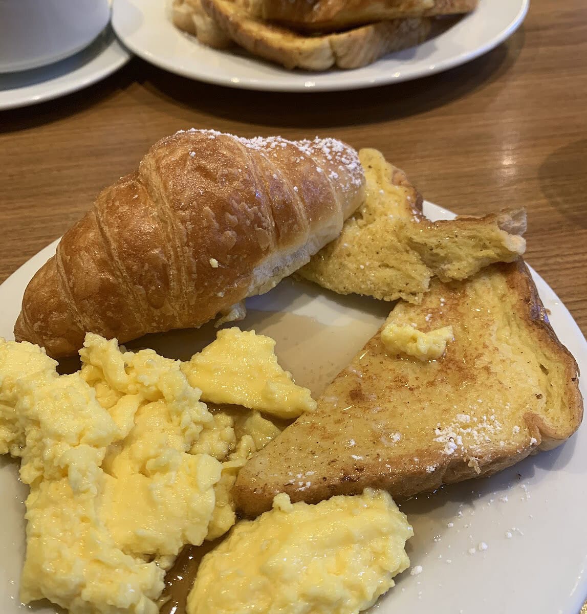 Breakfast plate consisting of french toast, scrambled eggs, and a croissant on the cruise ship.