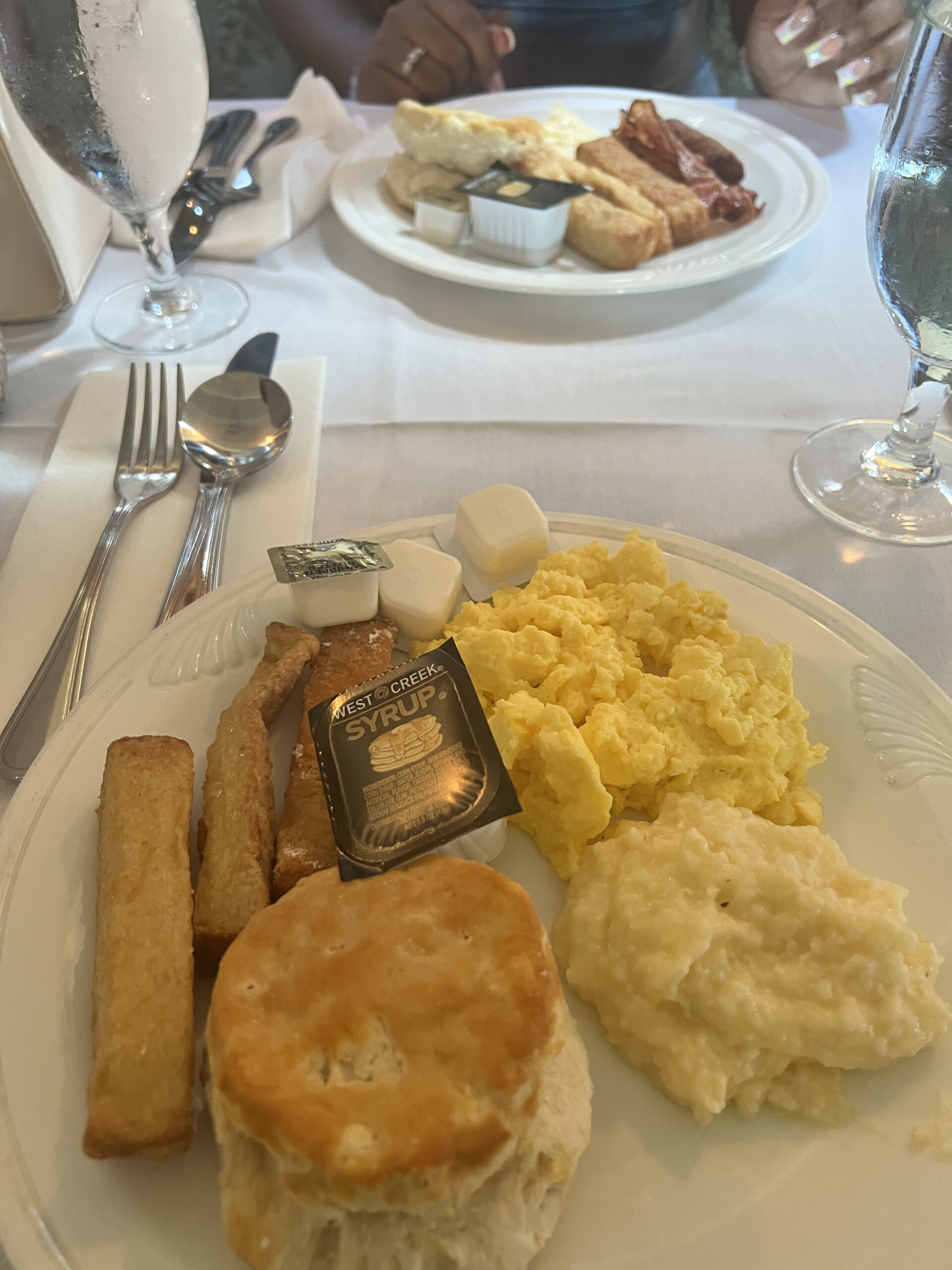 A breakfast plate with biscuit, eggs, and grits. 