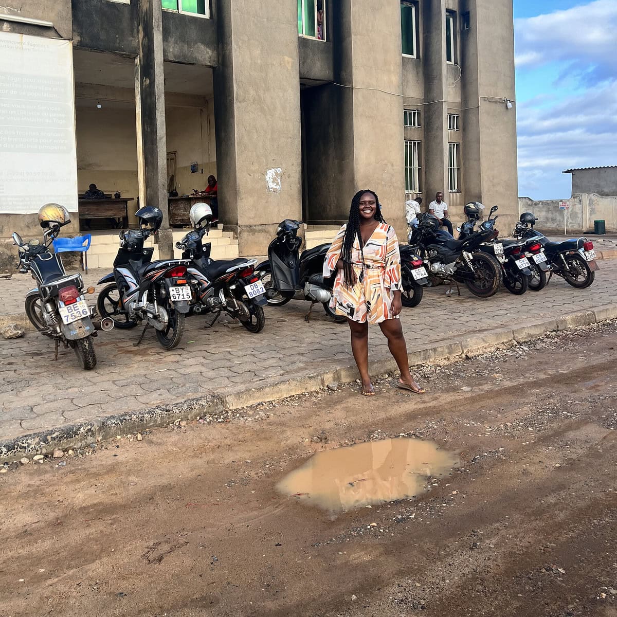 Blogger Christina Jane standing in front of a welcome sign in Togo. 