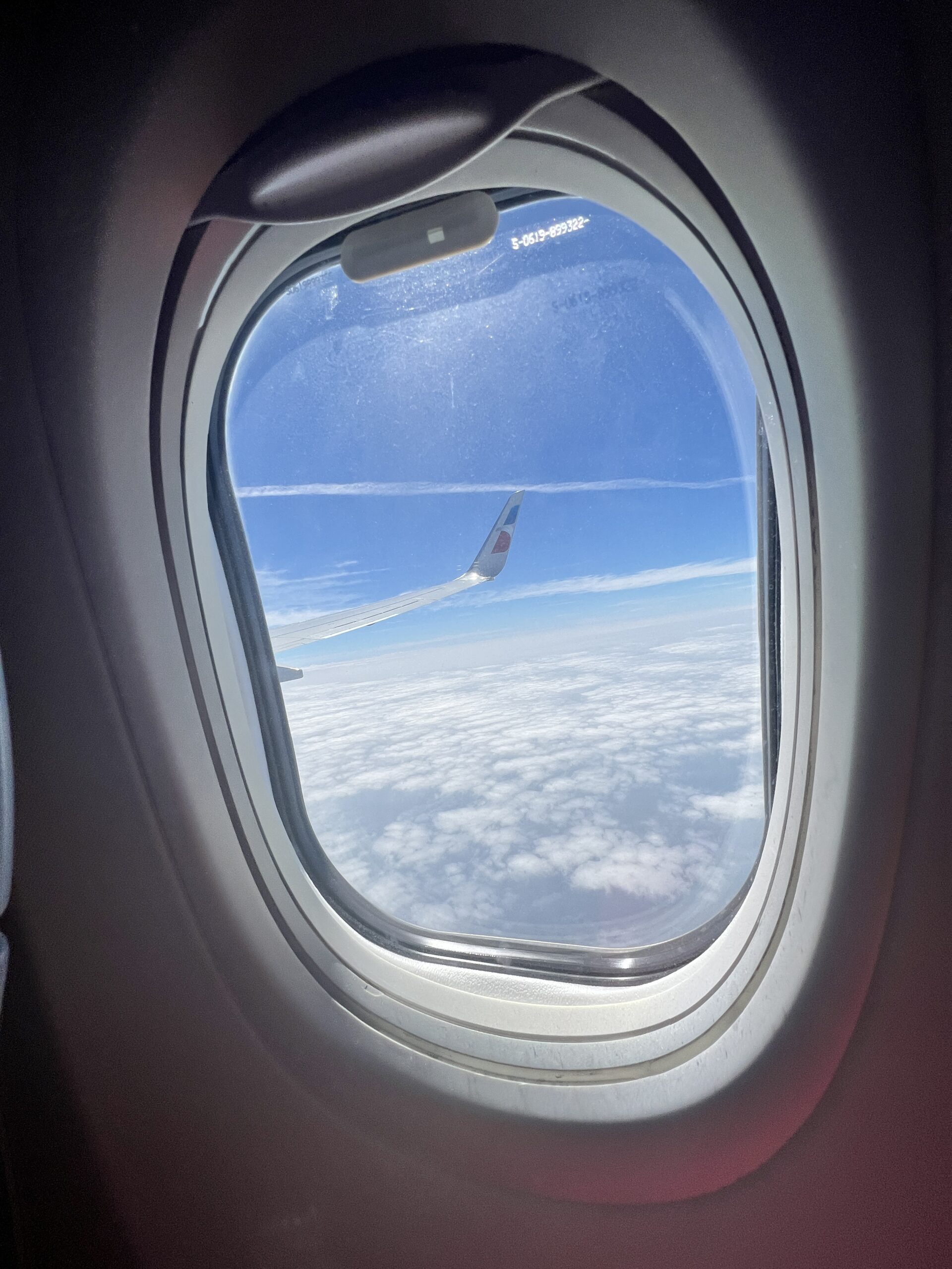 An image of an airplane window with views of the sky 